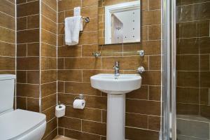 a bathroom with a sink and a toilet and a mirror at Lucky 8 Hotel in Ilford
