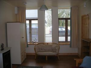 Cooraclare apartment في Cuar an Chláir: غرفة معيشة فيها كرسي وبعض النوافذ