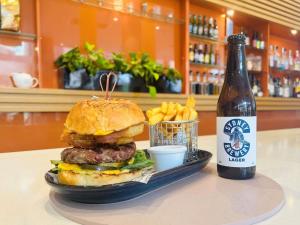 a hamburger and a bottle of beer and french fries at Novotel Newcastle Beach in Newcastle