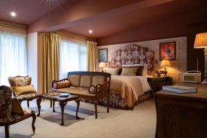 a bedroom with a bed and a couch and a table at The Potters Heron - A Heartwood Inn in Romsey
