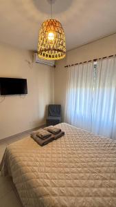 a bedroom with a bed and a chandelier and a chair at La casita in Río Cuarto