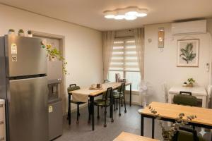 a kitchen with a refrigerator and tables and chairs at Ara Guesthouse in Busan