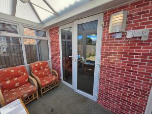 a screened porch with a couch and chairs on it at Mount Lavinia in Sheringham