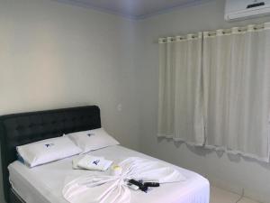 a bed with two white pillows with a bow on it at Paulos Pousada in Lagoa Santa