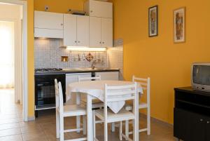 a kitchen with a table and chairs and a tv at Stintino Apartments in Stintino