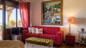 a living room with a red couch and a painting at Stintino Apartments in Stintino