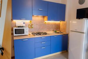 a kitchen with blue cabinets and a white refrigerator at Stintino Apartments in Stintino
