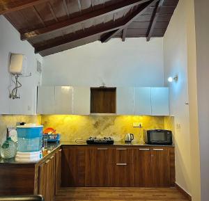a kitchen with wooden cabinets and a microwave at Himalayanblues cottages&stays in Mukteshwar