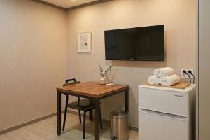 a room with a table and a television on a wall at Ara Guesthouse in Busan