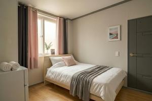 a small bedroom with a bed and a window at Ara Guesthouse in Busan