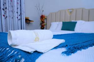 two beds with white pillows and a blue blanket at BUDDIEZ hotel limited in Kampala