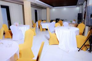 a banquet hall with white tables and yellow chairs at BUDDIEZ hotel limited in Kampala