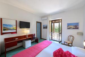 a bedroom with a bed and a desk and a television at Hotel Annabelle in Ischia Town