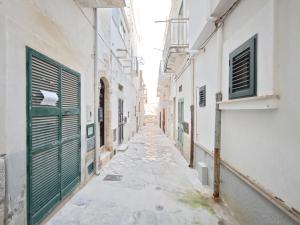 an alley with white buildings and green doors at Azzurro A Mare in Polignano a Mare