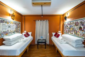 two white beds in a room with orange walls at Trekking Lodge Nepal in Kathmandu