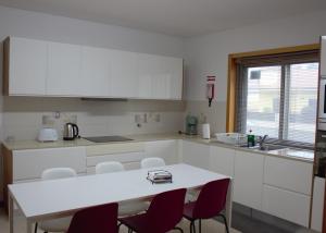 a kitchen with white cabinets and a white table and chairs at Alojamento Local Pando in Aveleda