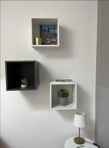 a tv on a wall with two shelves and a lamp at Casa di Giò - Comfy Lake Como Attic in Malgrate