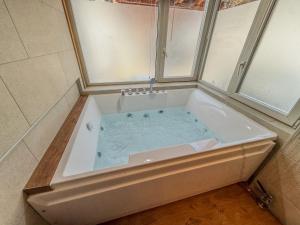 a bath tub with blue water in a bathroom at Chalet spa avec terrasses et vue panoramique in Leysin