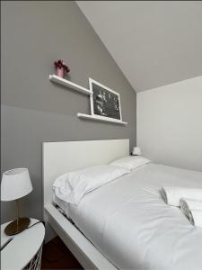 a white bedroom with two beds and a lamp at Casa di Giò - Comfy Lake Como Attic in Malgrate