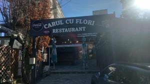 a sign for a restaurant with a car parked in front at Carul cu Flori in Craiova