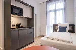 a small room with a bed and a kitchen at Homaris Rummelsburg Studios in Berlin