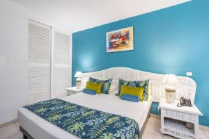 a bedroom with blue walls and a bed with yellow pillows at Karibea Squash Hôtel in Fort-de-France