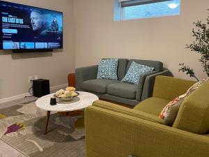 a living room with two couches and a tv at Mary's Luxury Suite in Winnipeg