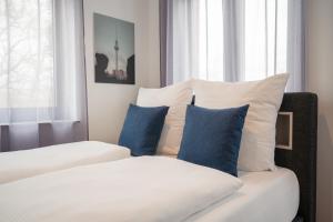 a bedroom with a bed with blue pillows at Homaris Rummelsburg Studios in Berlin