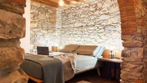 a bedroom with a bed and a stone wall at Poggio Belvento in Suvereto +63 photos