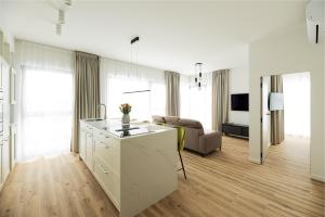 a white kitchen with a couch and a living room at Lighthouse View - Sol Marina in Wiślinka
