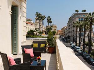 a balcony with chairs and a table on a city street at Hotel De Paris Sanremo in Sanremo