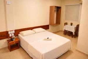 a bedroom with a white bed and a table and a chair at Frota Palace Hotel in Macapá