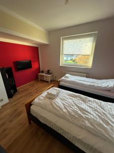 a room with two beds and a red wall at Ferienwohnung Fatlume No 5 n 6 in Bad Honnef am Rhein