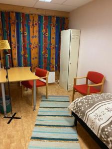 a bedroom with a desk and a bed and a table and chairs at Sentrumovernatting in Kjøllefjord