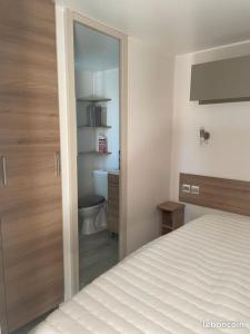 a bedroom with a bed and a bathroom with a toilet at Mobilhome Luminosa*** in Fréjus