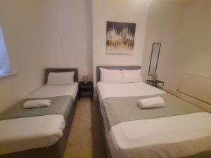 two beds in a small room with white sheets at Blyth 1 Bedroom Apartment in Blythe