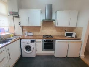 a kitchen with white cabinets and a washer and dryer at Blyth 1 Bedroom Apartment in Blythe +6 photos