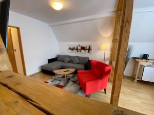 a living room with a red chair and a couch at "Landidyll"Hotel Rathaus in Wildemann