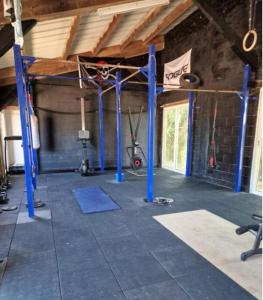 a gym with blue poles in a room at Petit Gîte à la campagne in Brains-sur-Gée