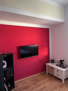 a room with a red wall with a tv on it at Ferienwohnung Fatlume No 5 n 6 in Bad Honnef am Rhein