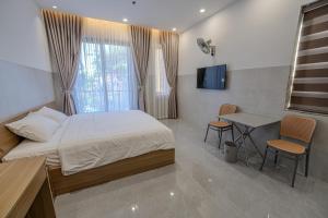 a bedroom with a bed and a table and a television at An Thy HOTEL in Vung Tau