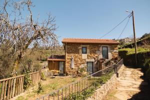 a stone house with a fence in front of it at Casa do Cancelo in Mondim de Basto