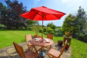 a table and chairs with a red umbrella at 1 Bed in Bergh Apton oc-1387 in Thurton