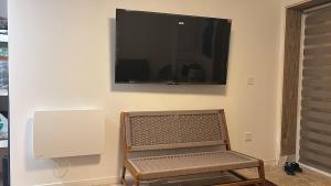 a tv on a wall with a chair and a bench underneath it at Chez mohamed in Mons-en-Baroeul