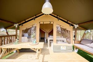 a tent with a table and a couch on a deck at Glamping Kamperland in Kamperland