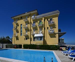 a yellow building with a swimming pool in front of it at Hotel Biagini in Rimini