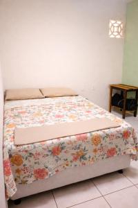 a bed with a floral blanket on it in a bedroom at Paraíso Pedra Encantada in Paracuru