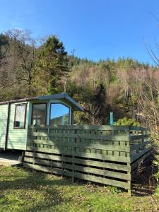 a green trailer is parked next to a fence at The Mosselle No 60 in Ardentinny