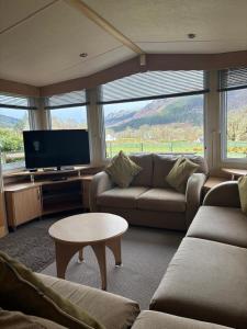 a living room with a couch and a tv and a table at The Mosselle No 60 in Ardentinny