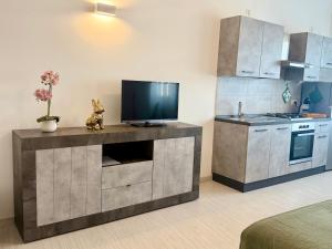 a kitchen with a flat screen tv on a cabinet at Loft moderno nel cuore del Centro Storico - spazioso & luminoso WiFi veloce- Tutto a piedi in Pordenone +8 photos
